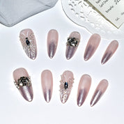 Set of elegant stiletto press-on nails laid out on a white background, featuring a pink ombre design with intricate 3D butterfly and fairy accents.