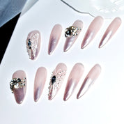 Detailed view of a set of elegant stiletto press-on nails on a white background, showcasing a pink ombre design with 3D butterfly and fairy accents