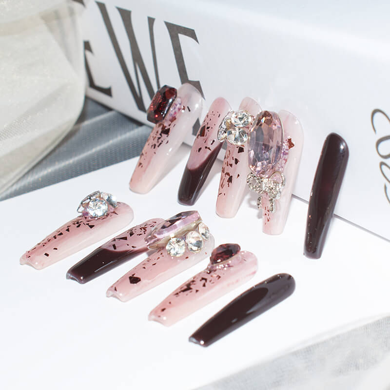 Elegant burgundy blush press-on nails with intricate designs and embellishments, presented on a white background