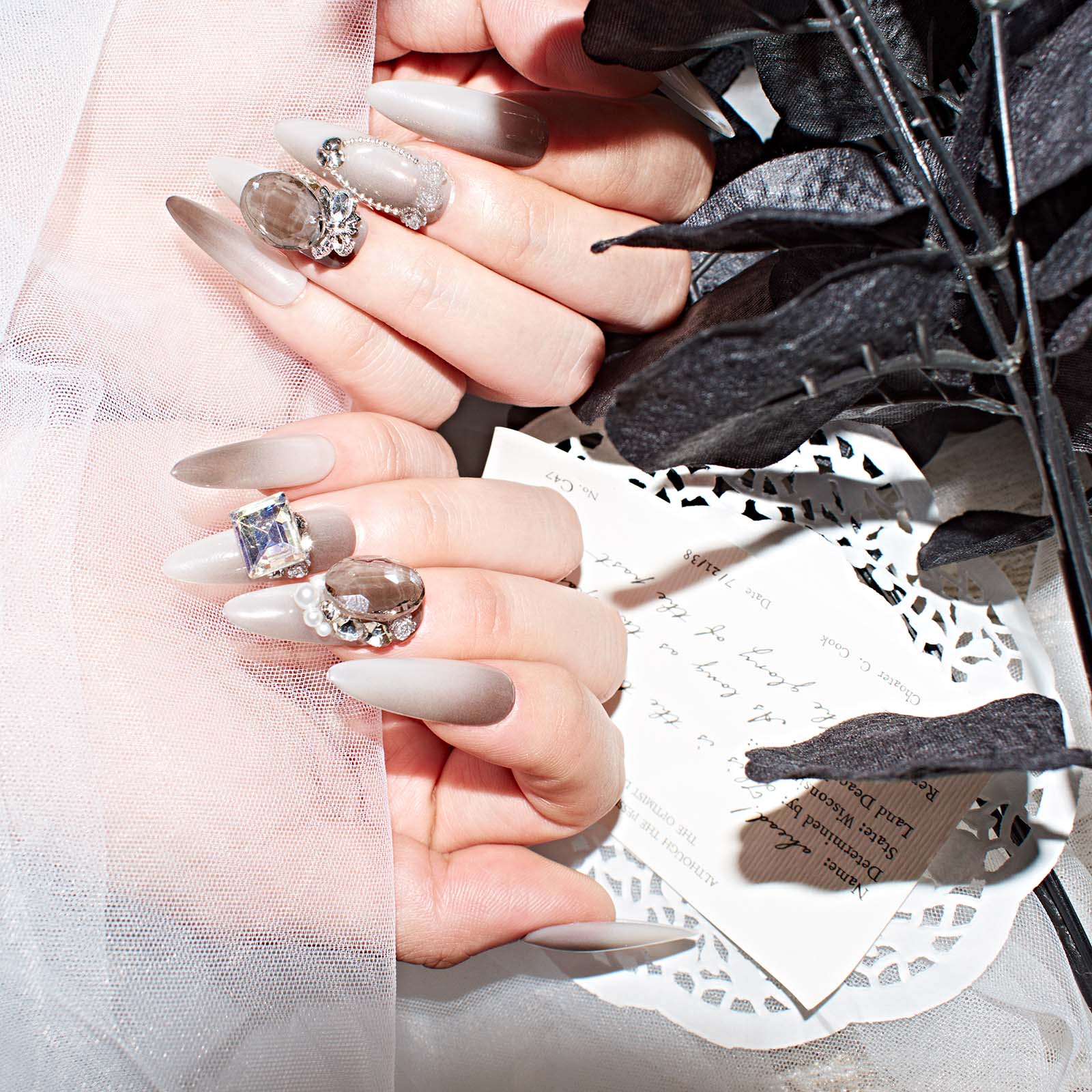 Hands showcasing brown ombre almond-shaped press-on nails with 3D pearls and rhinestones, highlighting their elegant and stylish design
