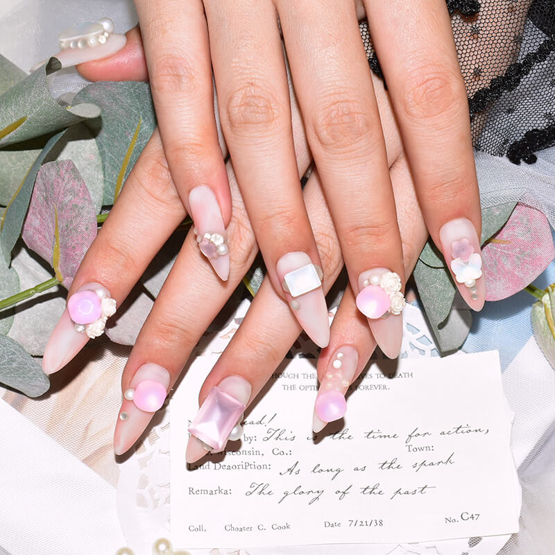Close-up of hands with pink candy matte press-on nails featuring 3D pearl and butterfly accents.
