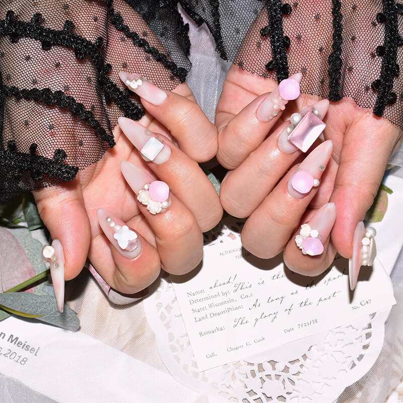Hands showcasing pink candy matte press-on nails with charming 3D pearl and butterfly accents