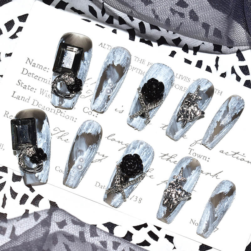 Set of Midnight Bloom on White Sands press-on nails displayed on a decorative card, highlighting the intricate 3D floral and chain designs