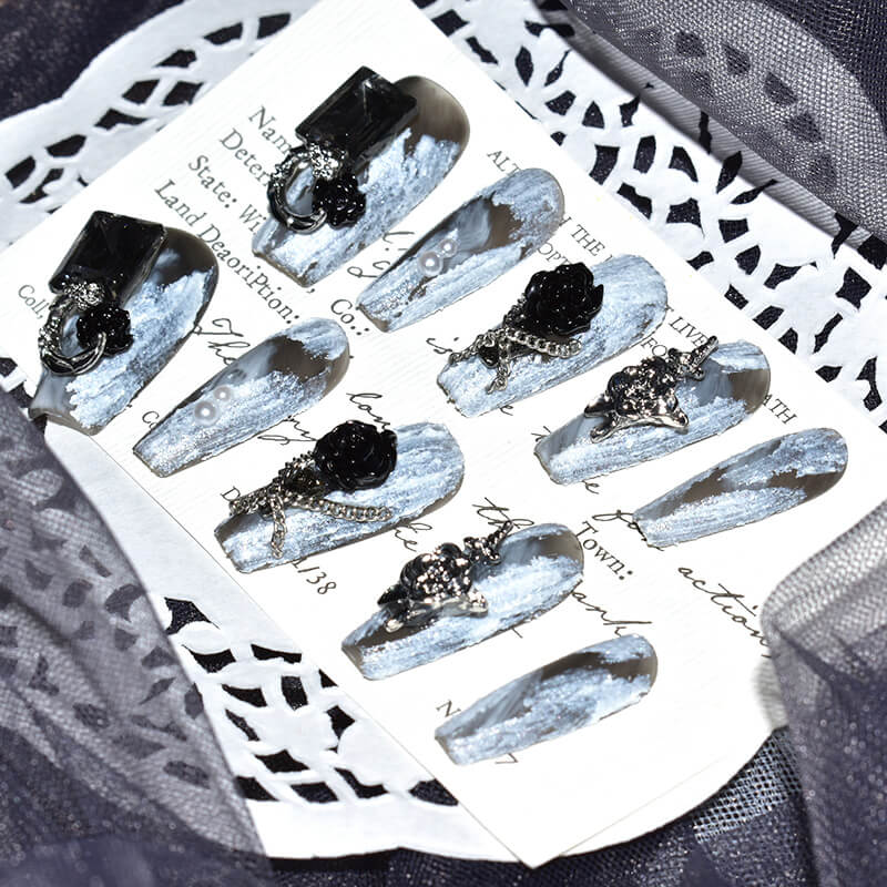 Elegant arrangement of Midnight Bloom on White Sands press-on nails, showcasing the white and black design with detailed 3D floral and chain accents